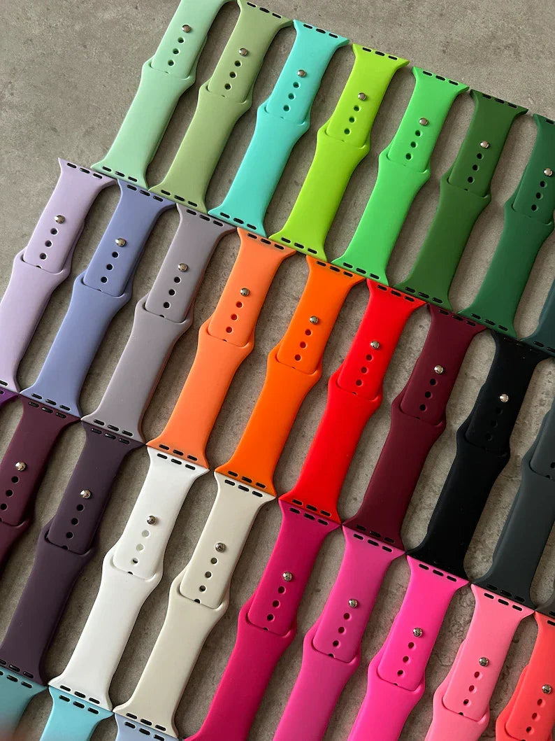 Colorful Apple Watch straps arranged neatly on a grey surface