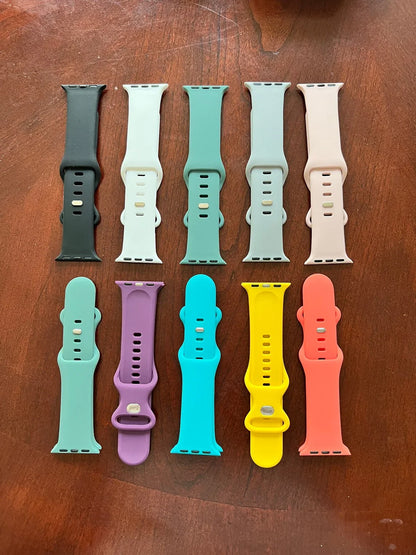 Colorful silicone Apple Watch straps in ten different colors on a wooden surface
