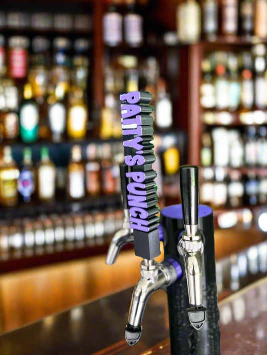 Two beer taps with 'Patty's Punch' branding against a blurred green plant background.
