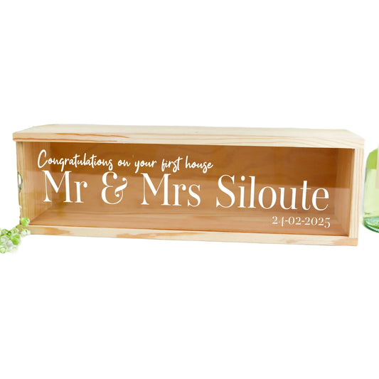 Wooden box with engraved text 'Congratulations on your first house Mr & Mrs Siloute' on a white background.