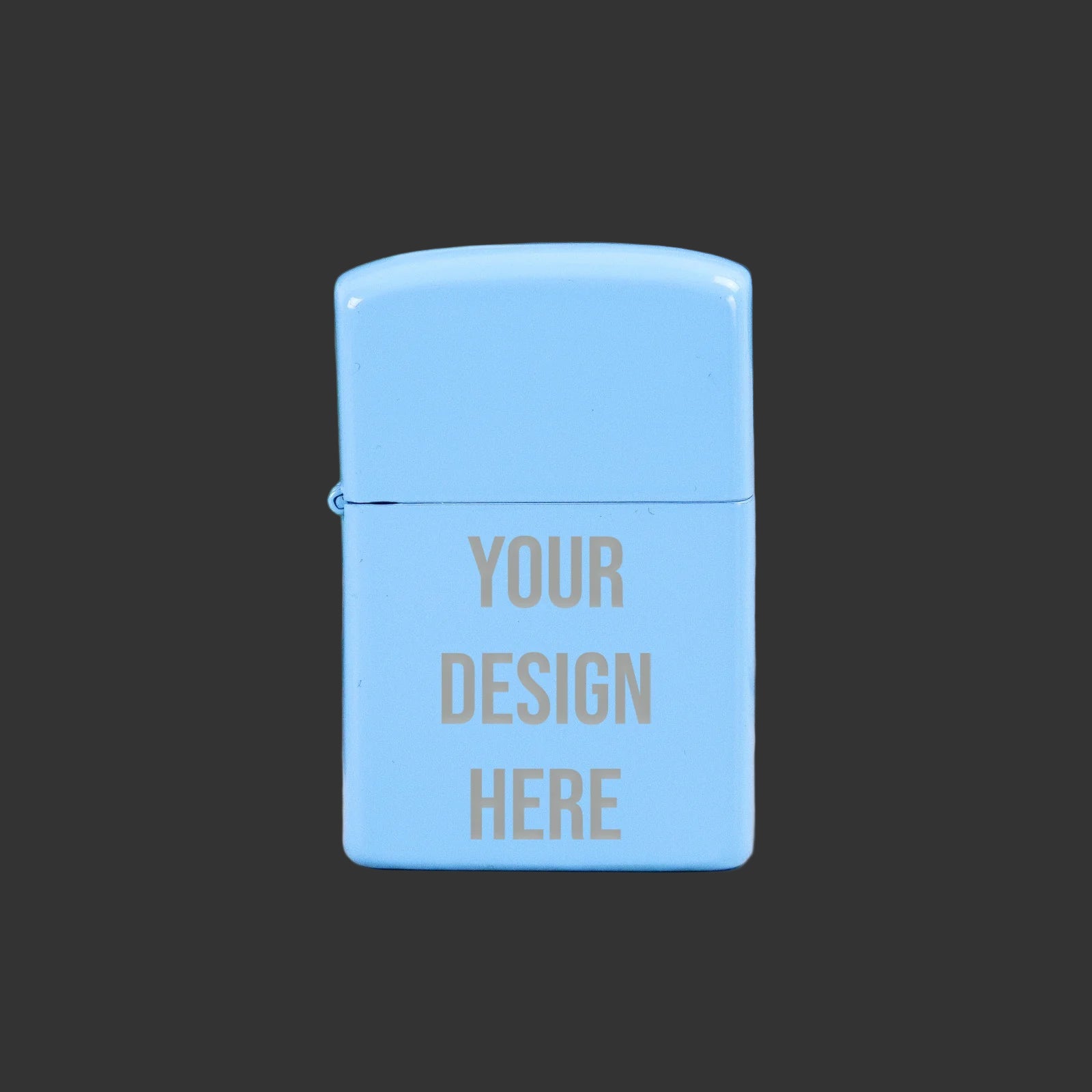 Light blue Zippo-style lighter with 'Your Design Here' text on a wooden surface with green leaves in the background