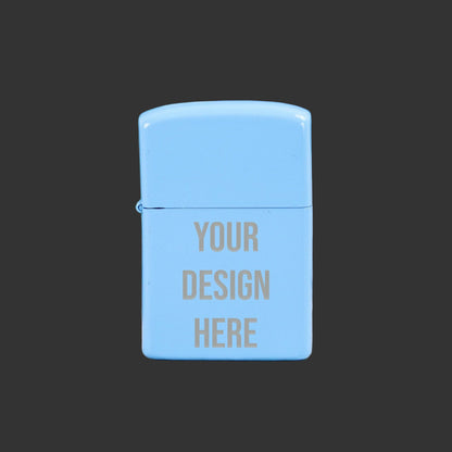 Light blue Zippo-style lighter with 'Your Design Here' text on a wooden surface with green leaves in the background