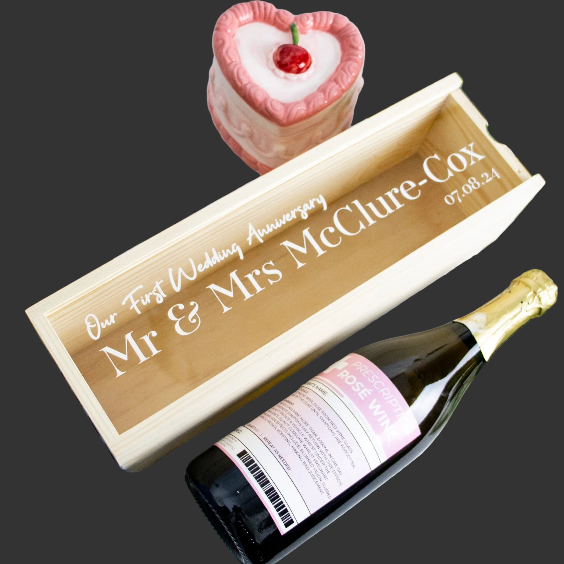 Personalized wine box with a bottle of wine and a small cake on a decorative background.