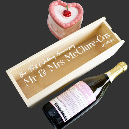 Personalized wine box with a bottle of wine and a small cake on a decorative background.