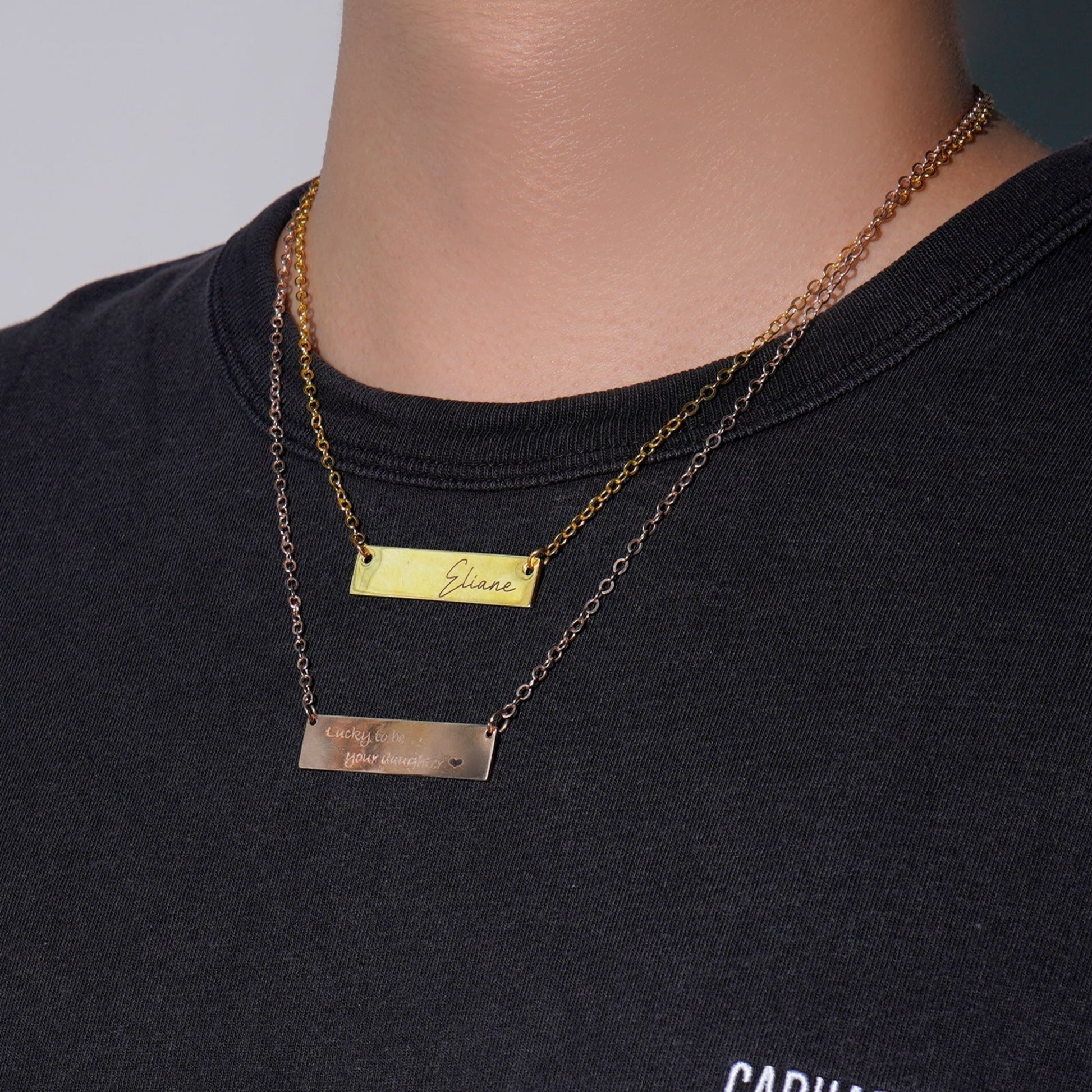 Gold necklace with rectangular pendants on a black shirt